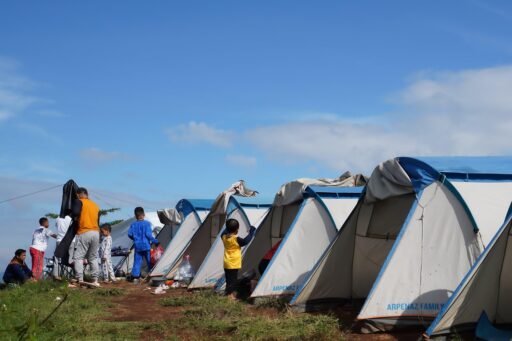 Een klassieke Nederlandse camping met tenten en klapstoelen op een grasveld, jaren tachtig sfeer