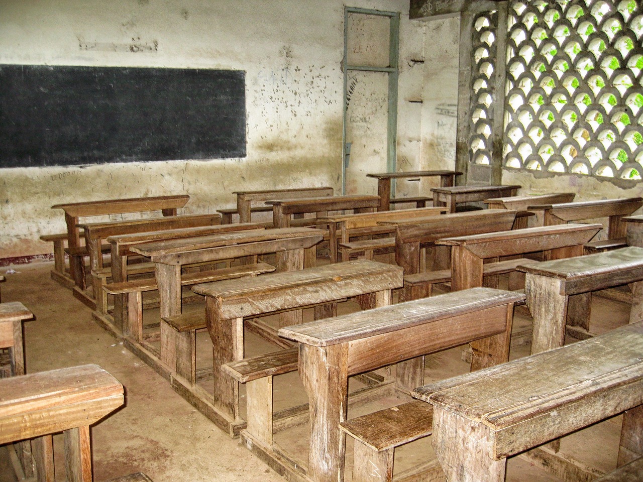 Een oud schoolbord in een klaslokaal met krijtletters, zoals kinderen vroeger bij grammaticalessen gebruikten