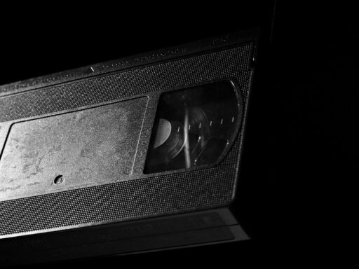 Kleurrijke VHS-hoezen op een rij in een videotheekschap, met handgeschilderde filmafbeeldingen