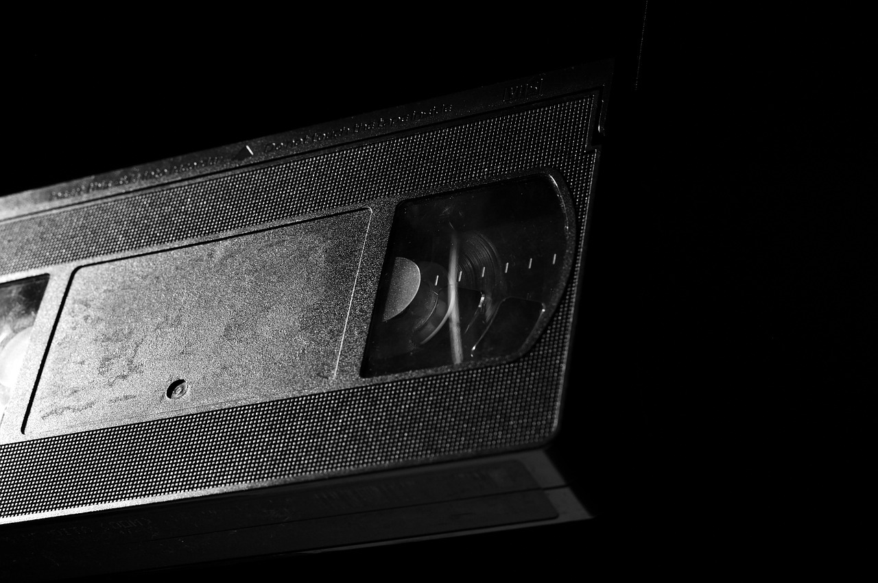 Kleurrijke VHS-hoezen op een rij in een videotheekschap, met handgeschilderde filmafbeeldingen