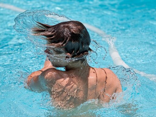 Een zonnig buitenzwembad met blauwe tegels en kinderen die spelen in het water
