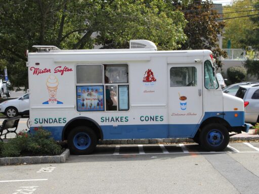 Een klassieke ijscowagen geparkeerd in een Nederlandse woonstraat op een zomerse dag