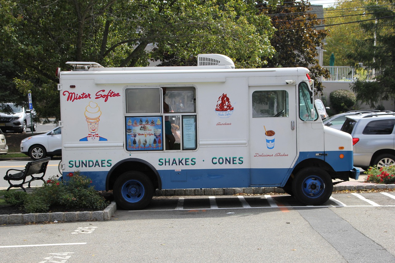 Een klassieke ijscowagen geparkeerd in een Nederlandse woonstraat op een zomerse dag