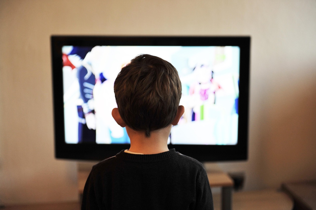 Kind in pyjama kijkt vroeg in de ochtend naar de televisie