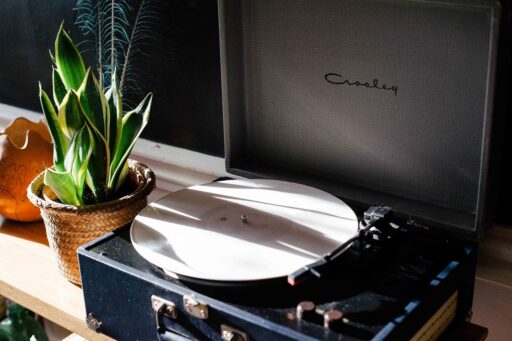 Een zilveren discman uit de jaren negentig op een houten tafel, met een cd half uit de speler
