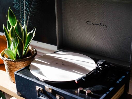 Een zilveren discman uit de jaren negentig op een houten tafel, met een cd half uit de speler