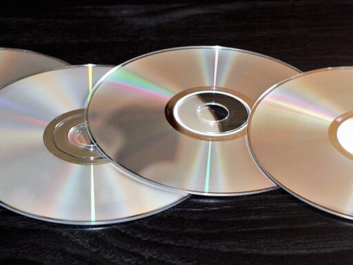 Een oude computer met cd-rom-lade open naast een stapel encyclopedieën uit de jaren negentig