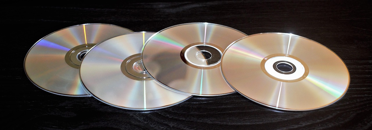 Een oude computer met cd-rom-lade open naast een stapel encyclopedieën uit de jaren negentig