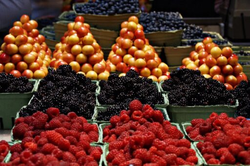 Een drukke Nederlandse markt van vroeger met kramen vol koopwaar en marktkooplieden in klederdracht