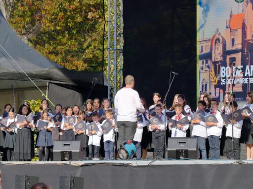 Kinderen zingen samen in een oude parochiezaal met houten banken
