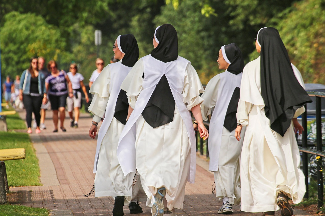 Een kind in een wit jeugdbewegingsuniform met das en muts, zoals bij de Patro vroeger