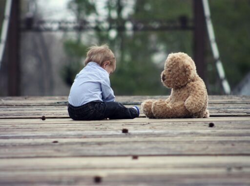 Een kind dat zijn neus in de nek van een oude, versleten teddybeer drukt