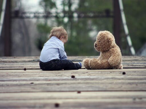 Een kind dat zijn neus in de nek van een oude, versleten teddybeer drukt