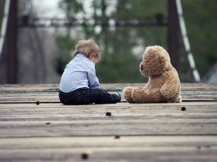Een kind dat zijn neus in de nek van een oude, versleten teddybeer drukt