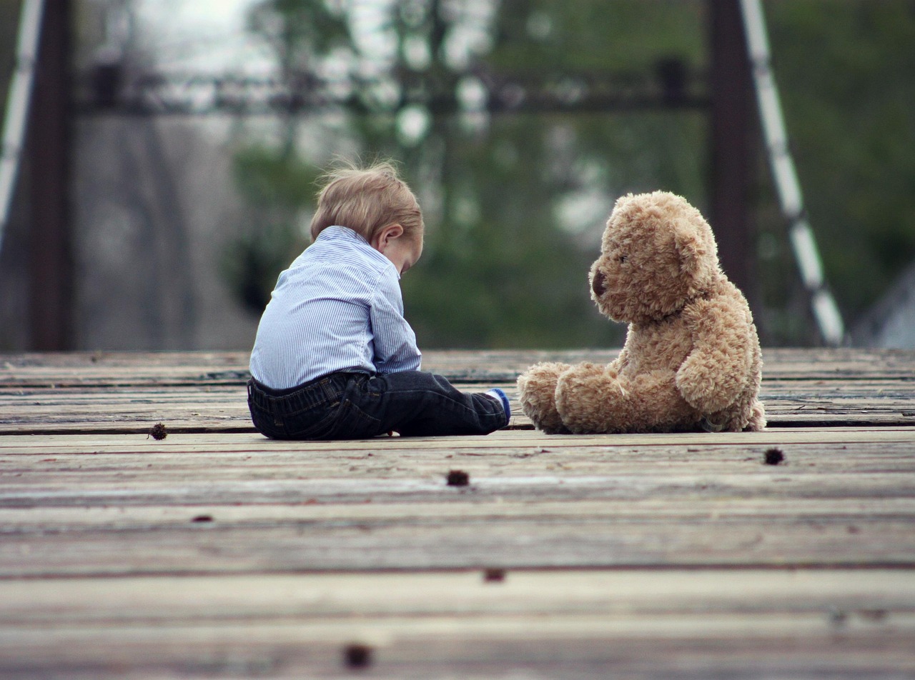 Een kind dat zijn neus in de nek van een oude, versleten teddybeer drukt